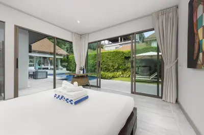 a bedroom with a large bed and large windows at Villa Mauri – Modern 3BR Villa with Private Pool in Kata Beach