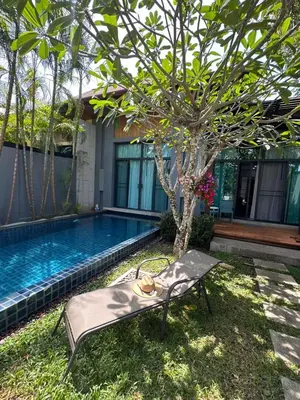 a chair next to a swimming pool with a tree at Cozy villa - perfect place to stay in Phuket in Ban Saiyuan (1)
