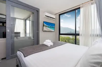 a bedroom with a large white bed and a window at Tropics Kamala CTG P615 - Corner 1 BR Apt Mountain view in Kamala Beach