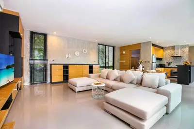 a living room with a white couch and a tv at Nature-Inspired 2BR Duplex P12 with pool and gym in Kamala Beach