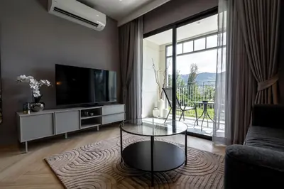a living room with a tv and a glass table at The Title Legendary Bangtao by Beringela in Bang Tao Beach