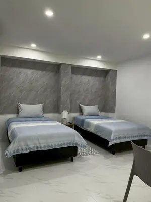 a bedroom with two beds and a chair in it at Nur Nur Residence and villa in Surin Beach