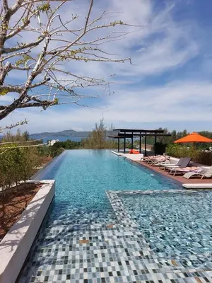 a swimming pool with chairs and an umbrella at 1 Bedroom l 6th Avenue l Surin beach in Surin Beach