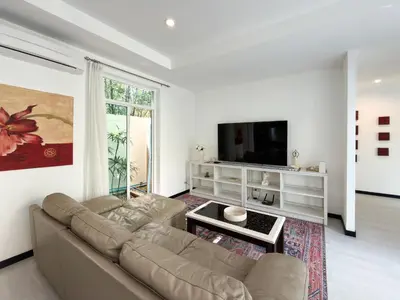 a living room with a couch and a flat screen tv at Nai Harn Family Pool Villa 4 bdr in Ban Saiyuan (1)