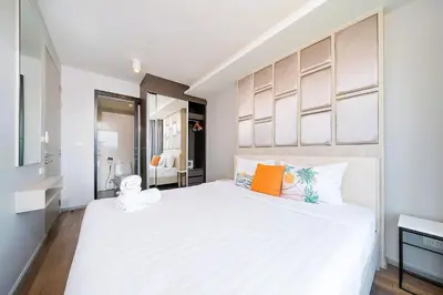 a bedroom with a large white bed with orange pillows at AVN 1 BR Apt near beaches 15mn walk in Surin Beach