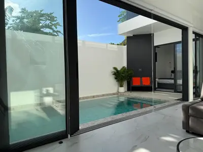 an indoor swimming pool in a house with glass walls at Brand new Luxury Pool Villa Seaview Rooftop in Ban Saiyuan (1)