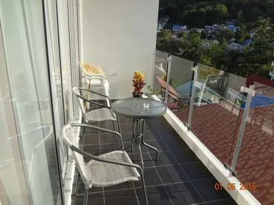 a glass table and chairs on a balcony at Karon Chic Seashore Apartment in Karon Beach