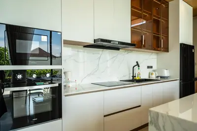 a kitchen with white cabinets and black appliances at Mouana Residence Song Khun Chalong 4-bedroom Pool Villa 896 in Chalong