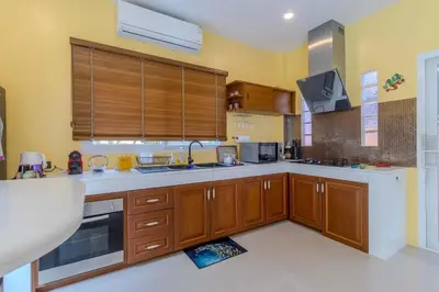 a kitchen with wooden cabinets and white counter tops at V225 Spacious 3BR Villa Pool and Garden Near Beach in Rawai Beach