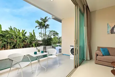 a living room with a glass table and chairs on a balcony at Spacious studio with access to the pool in Karon Hill condo in Karon Beach