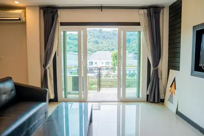 a living room with a couch and a large sliding glass door at Lulu Hotel at The Glasshouse Lion Café in Ban Sire