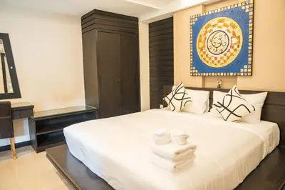 a bedroom with a white bed with a blue picture on the wall at Lulu Hotel at The Glasshouse Lion Café in Ban Sire