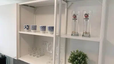 a white cabinet filled with glasses and vases at Cozy studio Sunset view near of MaiKhao beach in Ban Mai Salae