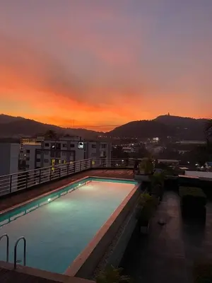 a swimming pool on top of a building with a sunset at Modern Apartment in Chalong in Chalong