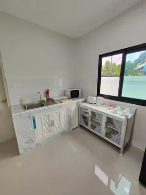 a white kitchen with a sink and a window at The White House Chalong in Chalong