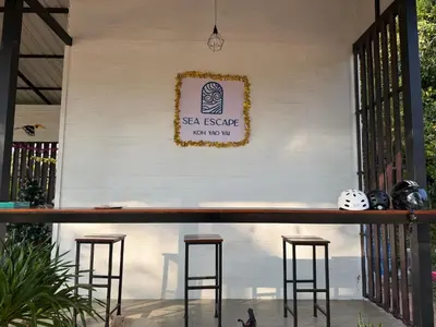a bar with stools in front of a white wall at Sea Escape Koh Yao Yai in Ko Yao Yai