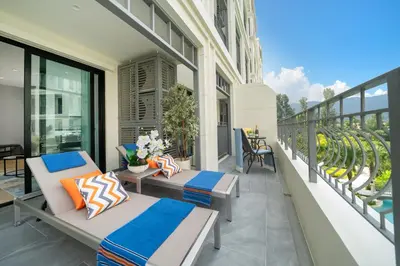 a balcony with two beds and tables on a building at The Title Legendary Condo with a large terrace 308 in Bang Tao Beach
