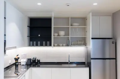 a kitchen with white cabinets and a stainless steel refrigerator at The Legendary Apartment 408 in Bang Tao Beach