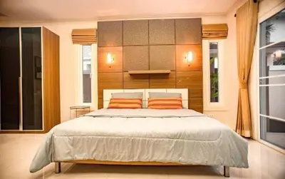 a bedroom with a large bed with two orange pillows at ZJ Garden Pool Villa in Phuket Town