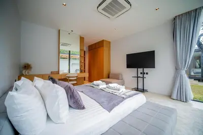 a bedroom with a large white bed with a flat screen tv at UltraLuxury 4BDR pool villa Botanica Foresta in Ban Phru Champa