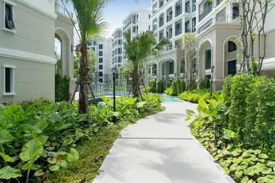 a walkway in front of a building with palm trees at Apartments 15 minutes walk from Bangtao Beach with a cinema in Phuket