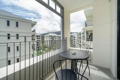 a balcony with a table and chairs and a window at Apartments 15 minutes walk from Bangtao Beach with a cinema in Phuket