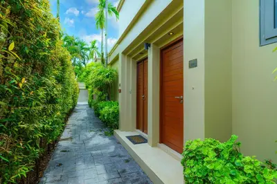 a walkway next to a house with a wooden door at The Residence One-Bedroom Villa in Ban Thalat Choeng Thale