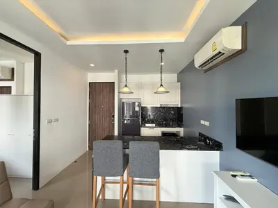 a kitchen with a counter and chairs in a room at Palmyrah Surin Apartments by Mill in Surin Beach