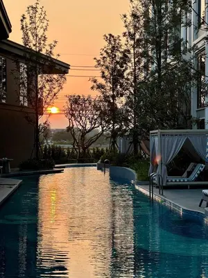 a swimming pool with the sunset in the background at New Studio in Bellevue Lagoon Phuket in Laguna Phuket