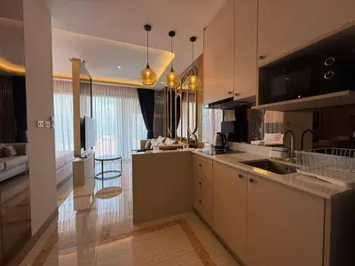 a kitchen with white cabinets and a living room at New Studio in Bellevue Lagoon Phuket in Laguna Phuket