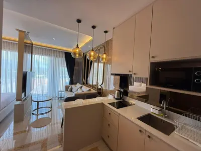 a kitchen with white cabinets and a living room at New Studio in Bellevue Lagoon Phuket in Laguna Phuket