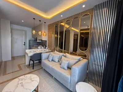 a living room with a blue couch and a kitchen at Bangtao new studio in Bellevue Lagoon in Laguna Phuket