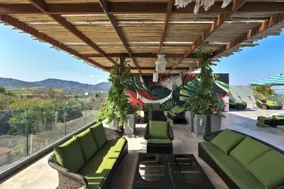 a patio with green couches and plants on a roof at Stylish apartments in Calypso Garden condo, Sea View! in Rawai Beach