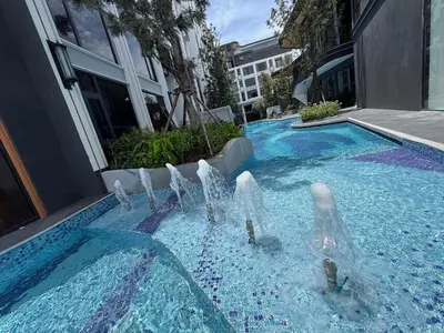 a swimming pool with a fountain in front of a building at New Apartment on the 1floor in The Proud Karon in Karon Beach