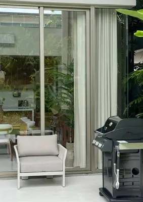a living room with a chair and a grill at Lake View Landscape Modern villa Bang Tao in Ban Thalat Choeng Thale