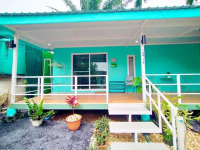 a green house with a porch and a deck at Palm Garden house 1 close to Bang Tao beach in Ban Phak Chit