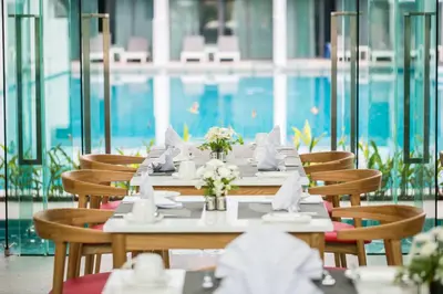 a dining room with tables and chairs and a pool at BlueSotel Krabi AoNang Beach in Ao Nang Beach