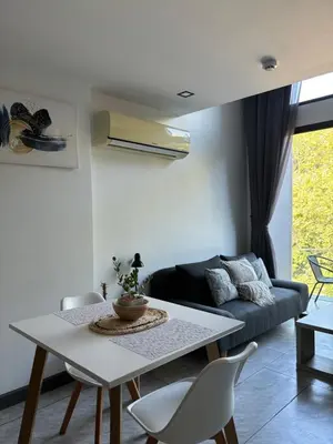 a living room with a table and a couch at Utopia Lofts by Sabai Sands in Nai Harn Beach