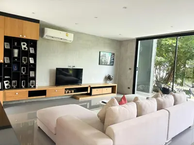a living room with a white couch and a tv at Design Duplex Pavillion 2 BR Natural Park P11 in Kamala Beach