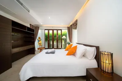 a bedroom with a large white bed with orange pillows at Tropical Pool Villa Thai-modern Villa with an OFFICE in Phuket Town