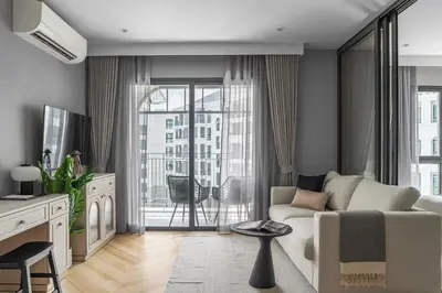 a living room with a couch and a large window at The Title Legendary Elegant Suite Bangtao in Ban Thalat Choeng Thale