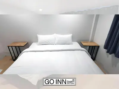 a bed in a room with two tables at XX GO INN Phuket Old Town โก อินน์ ภูเก็ต ย่านเมืองเก่า in Phuket Town