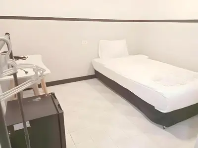 a bed in a hospital room with a suitcase at XX Mitr Inn - ภูเก็ต เมืองเก่า Phuket Old Town 2 in Phuket Town