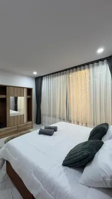 a large white bed in a bedroom with curtains at Bang Jo Garden Home in Koh Lone