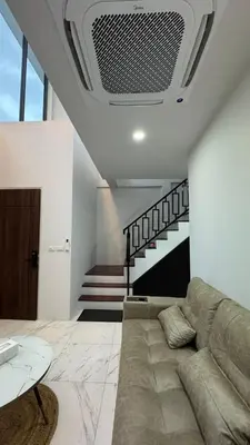 a living room with a couch and a staircase at Bang Jo Garden Home in Koh Lone