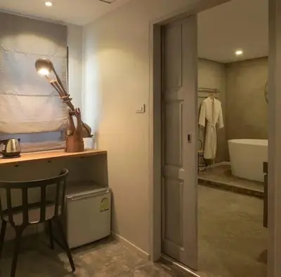 a bathroom with a table and a chair and a bath tub at Baan Chang Sanctuary in Laguna Phuket