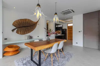 a dining room with a wooden table and white chairs at V259 Great for Relaxing with Pool & Full Amenities in Thalang