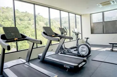 a gym with two exercise bikes in a room with windows at Utopia Karon Sea View Apartments in Karon Beach