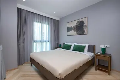 a bedroom with a large bed with green pillows at Title Legendary Bang Tao by My Home Phuket in Ban Nong Chaeng