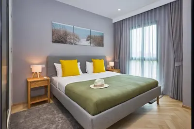 a bedroom with a large bed with yellow pillows at Title Legendary Bang Tao by My Home Phuket in Ban Nong Chaeng